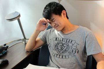 Male student looking stressed while trying to study from a notebook.