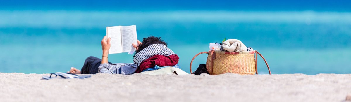 Person laying on the beach reading